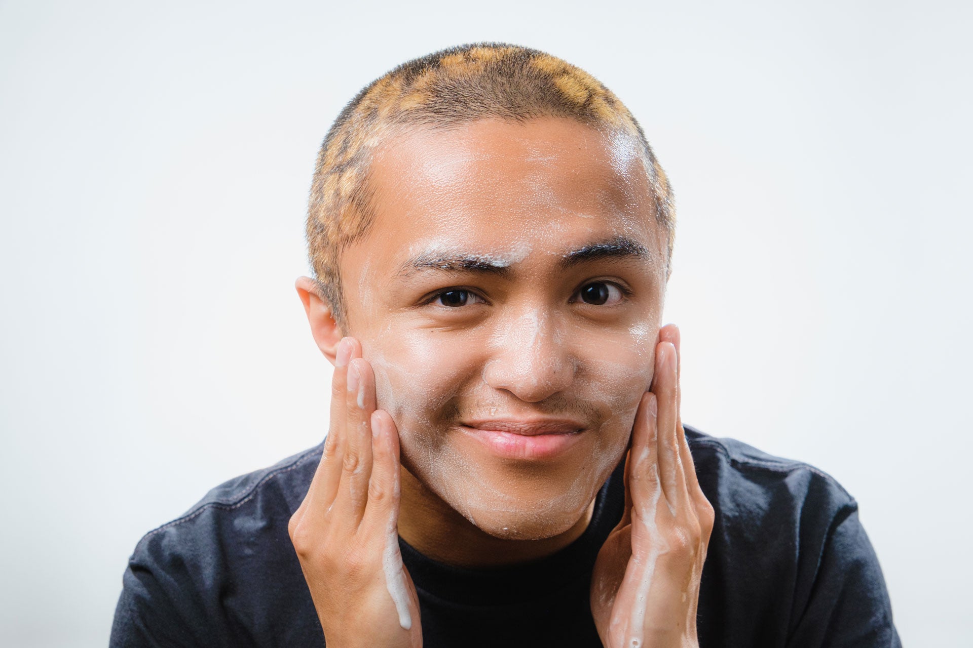 Young asian man talent model using Tyr Skincare facial cleanser, close up angle straight on