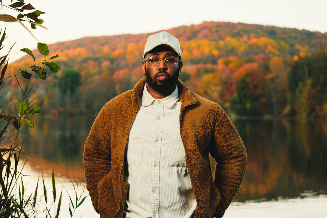 Young black man looking directly forward with foliage autumn leaves in the background