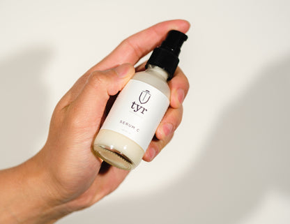 Tyr Skincare for me Serum C isolated in white background and held up by male hand, straight on angle